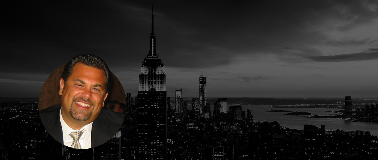 A profile photo of Mark S. Ricciardi with a circular crop, featuring a black and white photograph of New York City in the background.