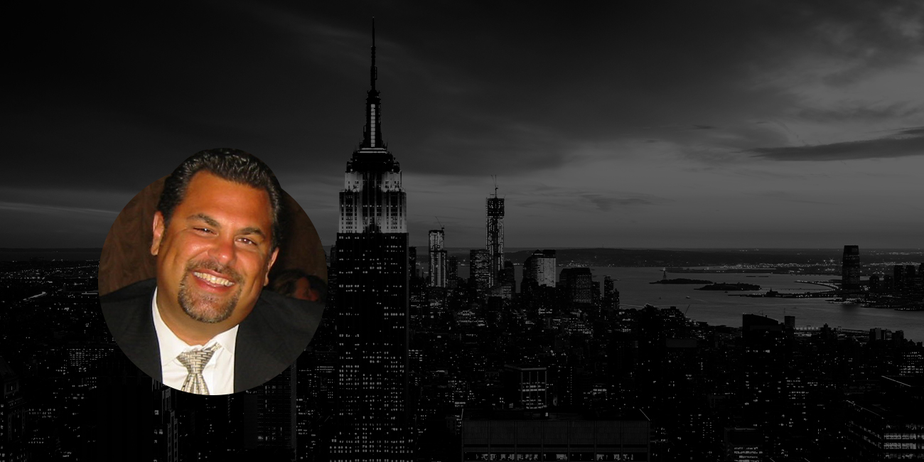 A profile photo of Mark S. Ricciardi with a circular crop, featuring a black and white photograph of New York City in the background.